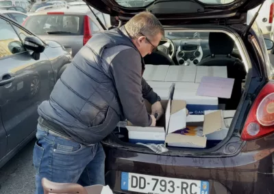 Un homme prépare des magazines dans le coffre d'une voiture pour la distribution.